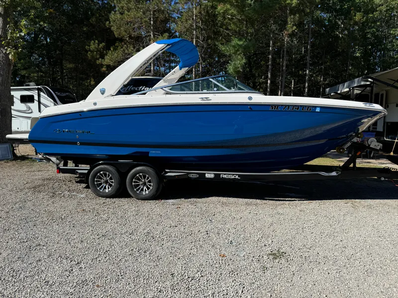 Slide: The Image of 2018 Regal 26 FasDeck boat in blue on a trailer, parked outdoors. - 3