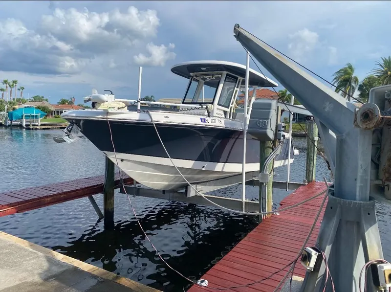 Slide: The Image of 2021 Robalo R272 Center Console boat docked on a lift by the water. - 2