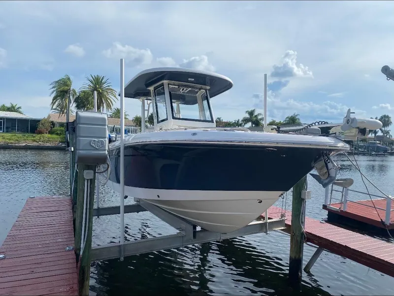 Slide: The Image of 2021 Robalo R272 Center Console boat docked on a lift by the water. - 5