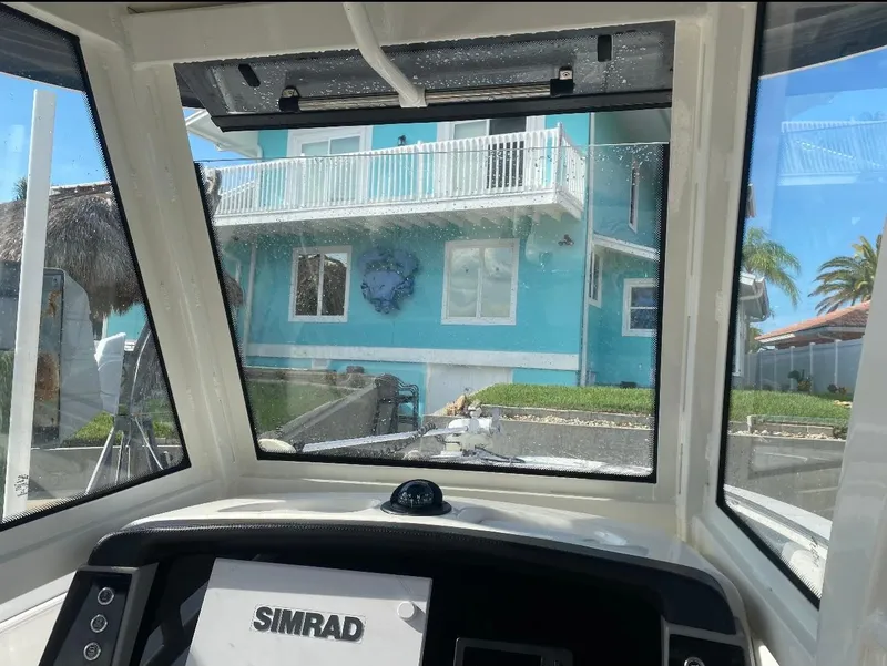 Slide: The Image of View from 2021 Robalo R272 Center Console boat, featuring Simrad navigation, facing a turquoise house. - 6