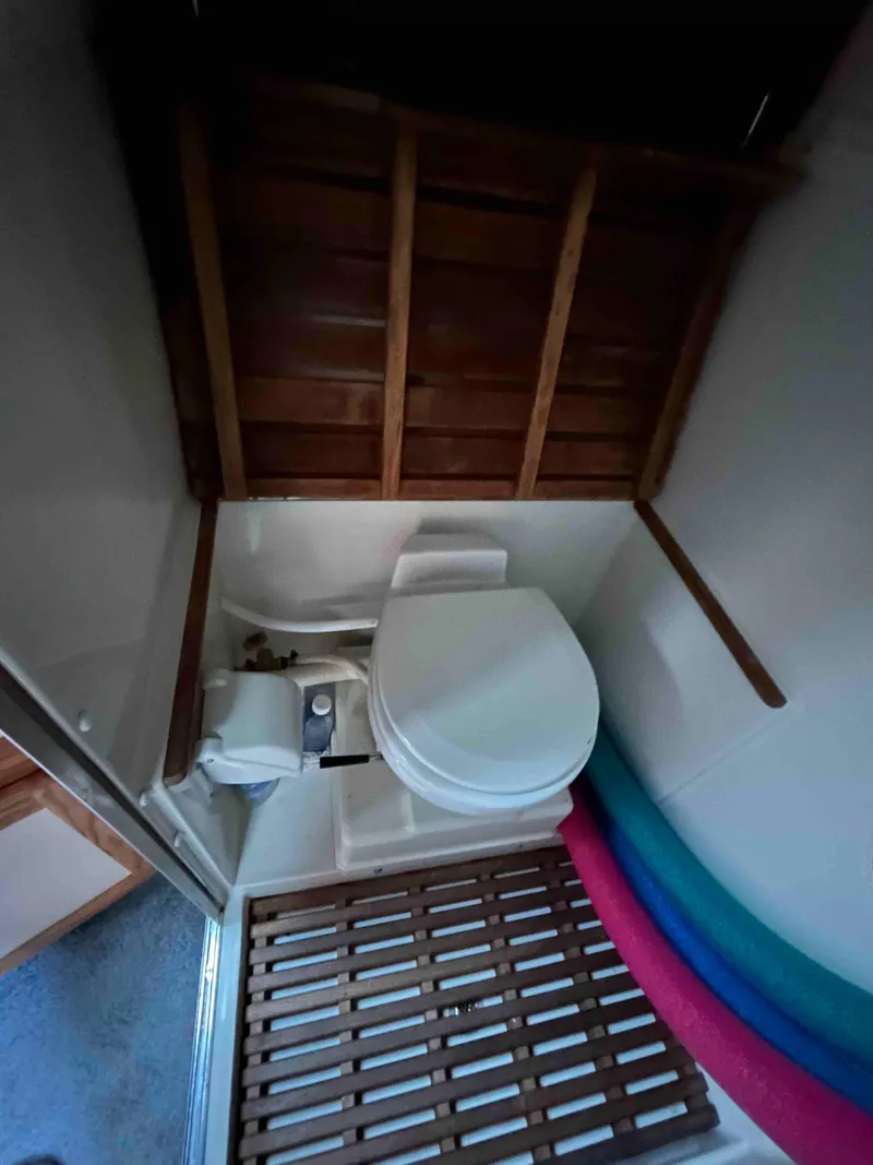 Slide: The Image of 1986 Silverton 31 Convertible boat bathroom with wooden accents and compact toilet. - 19