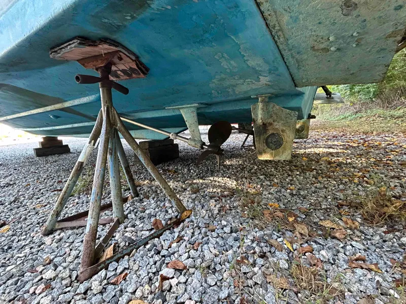 Slide: The Image of 1986 Silverton 31 Convertible boat hull on stands, resting on gravel. - 23