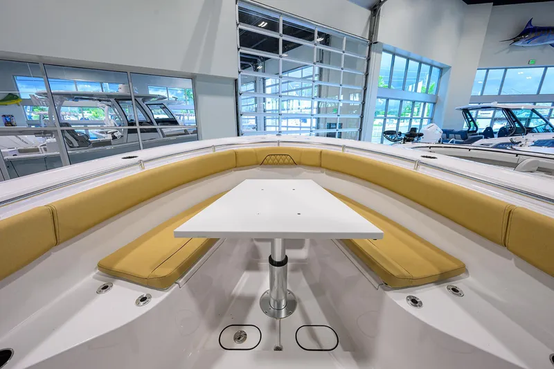 Slide: The Image of 2025 Sportsman Open 282 Center Console boat interior with seating and table in showroom. - 8