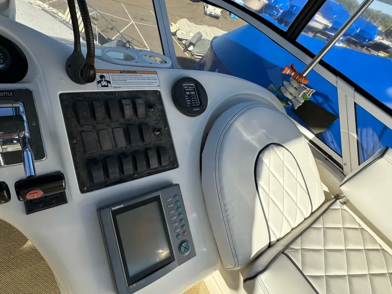 Slide: The Image of 1996 Sea Ray 400 Sedan Bridge helm with control panel and cushioned seat. - 21