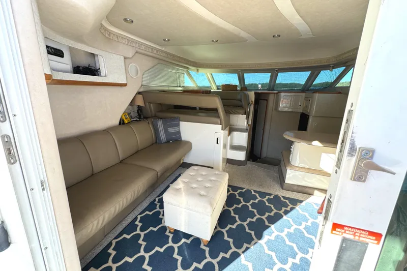 Slide: The Image of Interior of 1996 Sea Ray 400 Sedan Bridge with beige seating and blue patterned rug. - 30