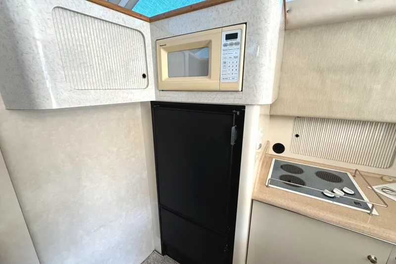 Slide: The Image of 1996 Sea Ray 400 Sedan Bridge kitchen with microwave, fridge, and stove. - 38
