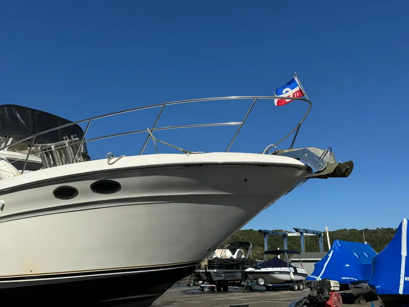 Slide: The Image of 1996 Sea Ray 400 Sedan Bridge yacht with flag, docked under clear blue sky. - 9