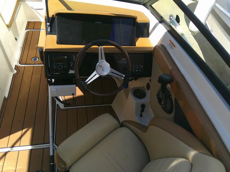 Slide: The Image of 2018 Sea Ray SPX 230 boat cockpit with tan seating and wood accents. - 16