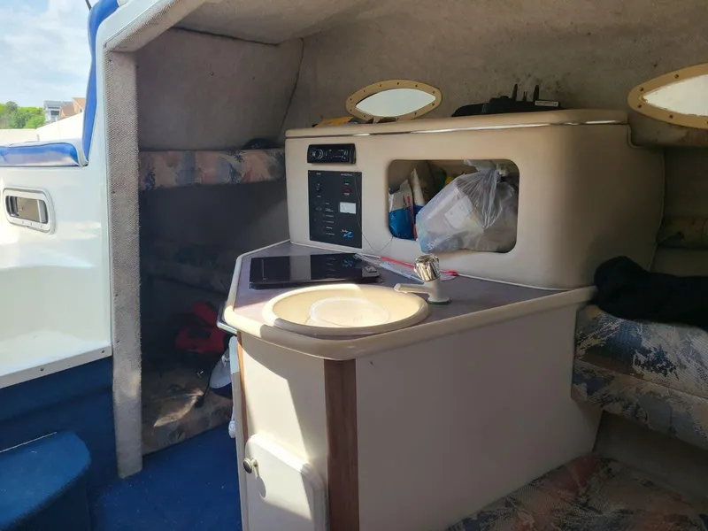 Slide: The Image of Interior of a 1996 Sea Ray 240 Sundancer boat, featuring a compact cabin and kitchenette. - 4