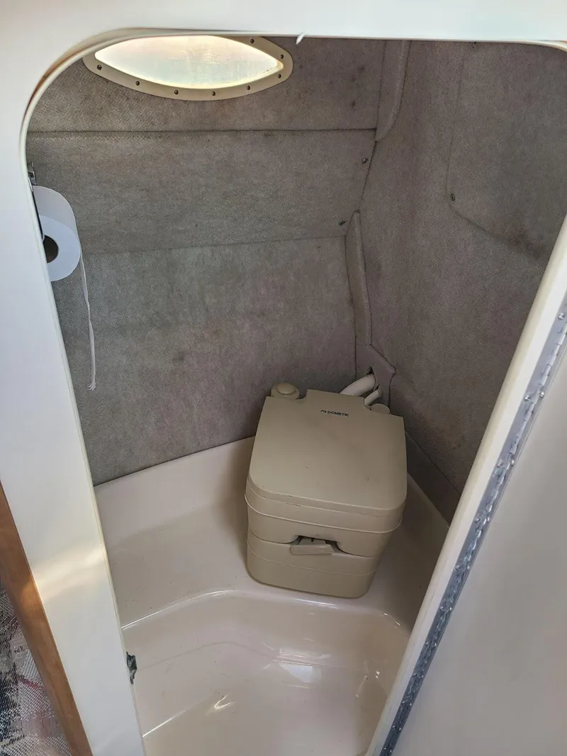 Slide: The Image of 1996 Sea Ray 240 Sundancer boat bathroom with portable toilet and compact design. - 8