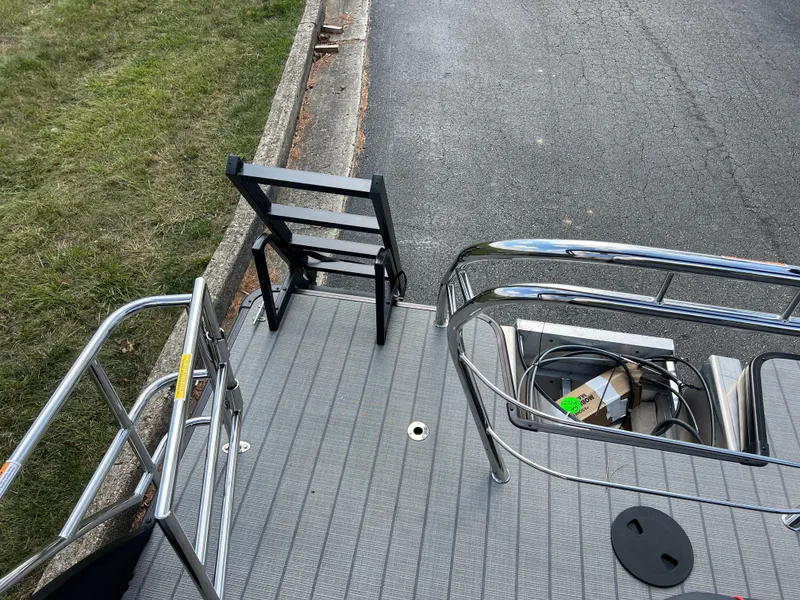 Slide: The Image of 2025 Godfrey SWEETWATER 2286 SFL boat deck with chair and railing, parked on roadside. - 22