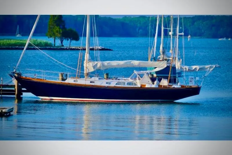 The Image of 1971 Hinckley Bermuda 40 sailboat docked on a serene lake. - 0