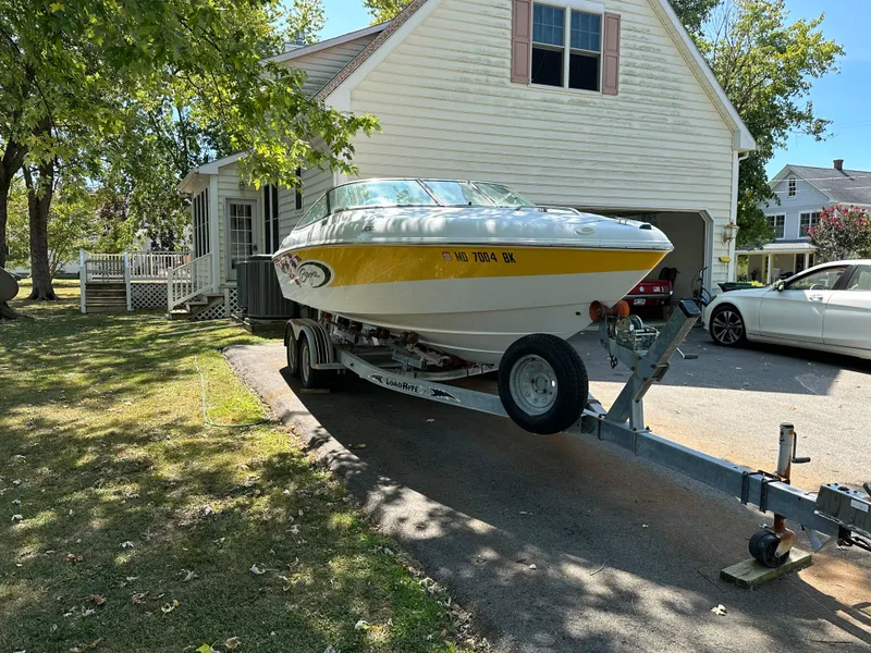 Slide: The Image of 2001 Baja 232 boat on trailer parked in driveway near house. - 2