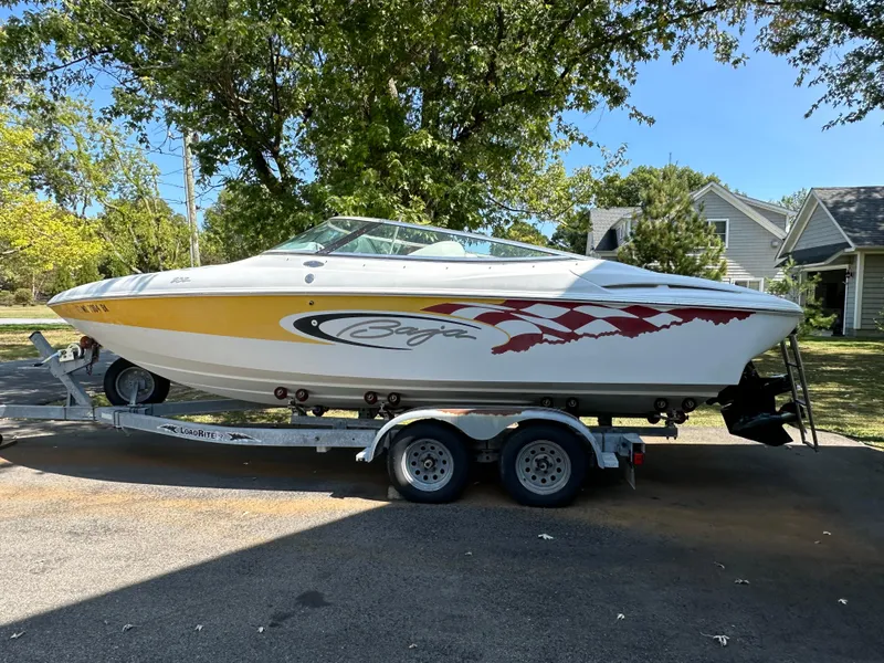 Slide: The Image of 2001 Baja 232 speedboat on trailer, featuring vibrant graphics, parked outdoors. - 26