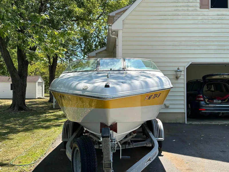 Slide: The Image of 2001 Baja 232 boat on trailer, parked beside a house with trees in the background. - 28
