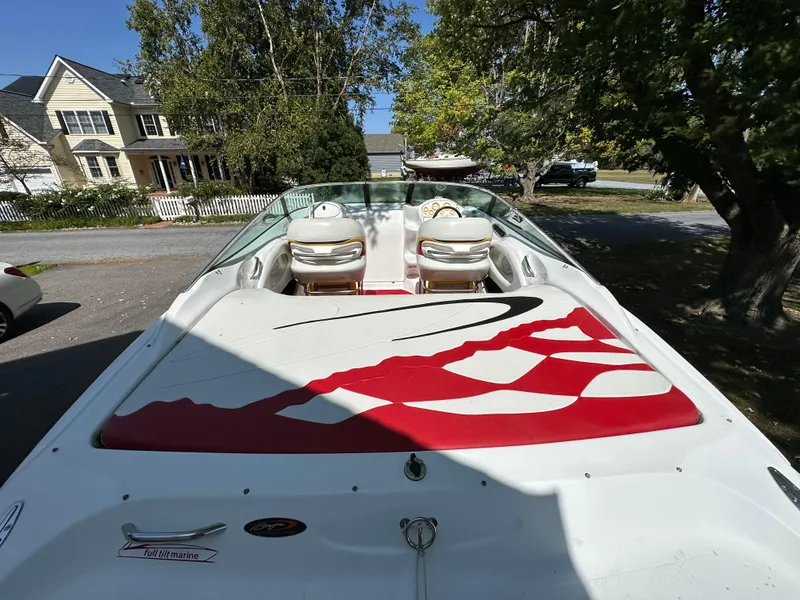 Slide: The Image of 2001 Baja 232 boat with red and white design, parked near houses and trees. - 5
