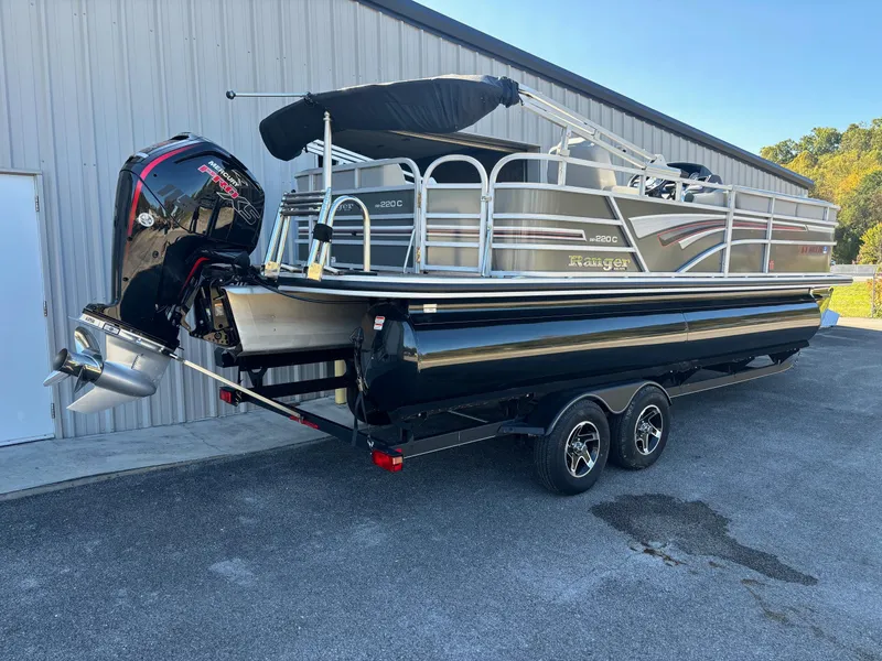 Slide: The Image of 2023 Ranger Reata 220C pontoon boat on trailer, parked near a building. - 12