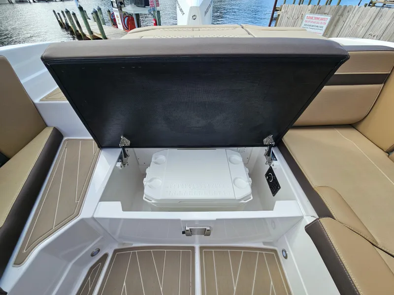 Slide: The Image of 2025 Monterey 235SS boat with open storage compartment, brown seating, and water view. - 18