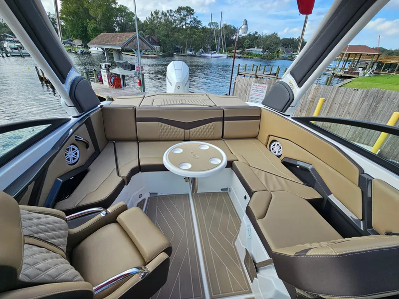 Slide: The Image of 2025 Monterey 235SS boat interior with luxurious seating and table, docked by a scenic waterfront. - 19
