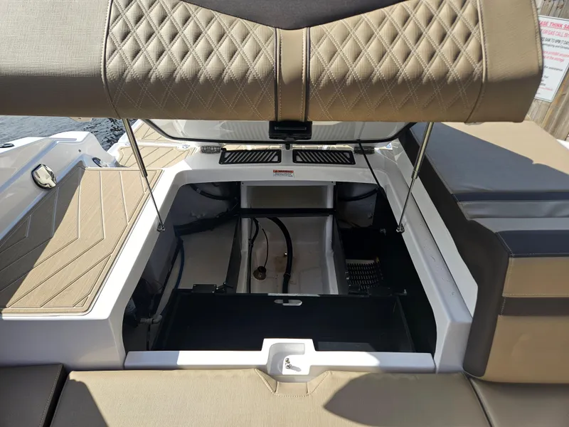 Slide: The Image of 2025 Monterey 235SS boat interior with open storage compartment and cushioned seating. - 29