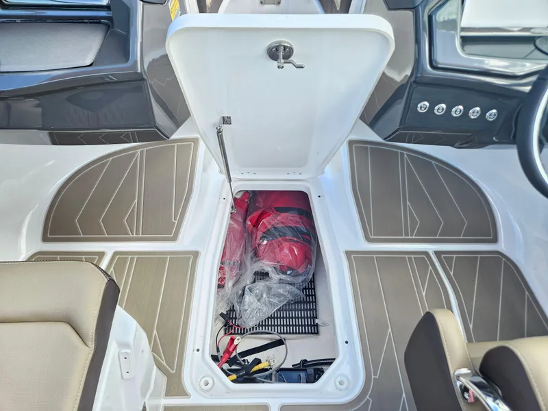 Slide: The Image of Open storage compartment in 2025 Monterey 235SS boat, showing safety equipment and accessories. - 31