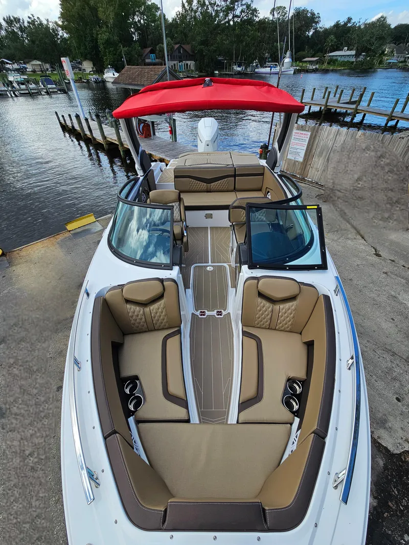 Slide: The Image of 2025 Monterey 235SS boat with red canopy, docked by a serene waterfront. - 32