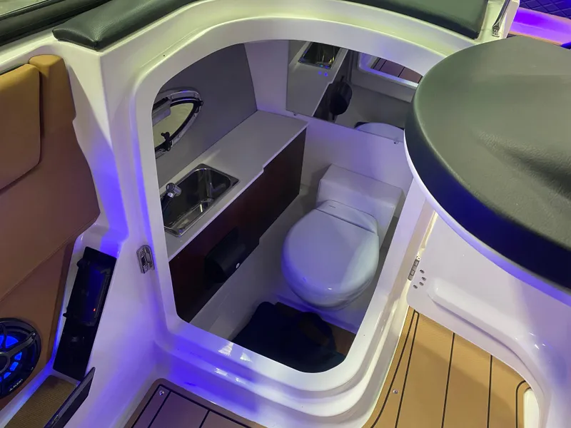 Slide: The Image of 2025 Chaparral 26 Surf boat interior with compact bathroom and sink. - 11