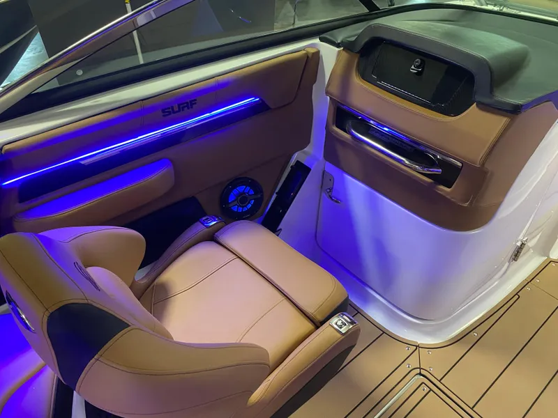 Slide: The Image of 2025 Chaparral 26 Surf boat interior with modern seating and ambient blue lighting. - 6