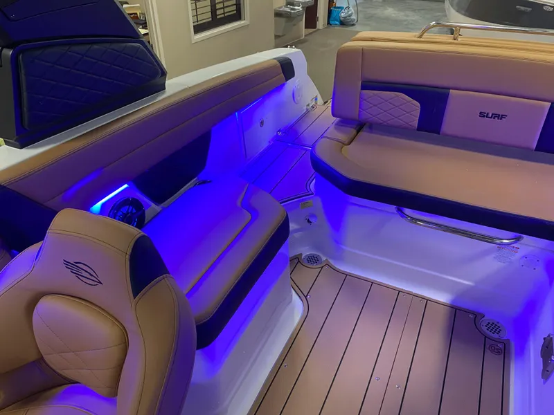 Slide: The Image of 2025 Chaparral 26 Surf boat interior with blue LED lighting and tan seating. - 8