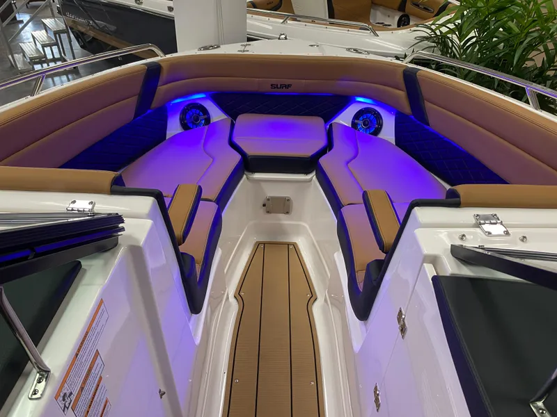 Slide: The Image of 2025 Chaparral 26 Surf boat interior with blue LED lighting and cushioned seating. - 9