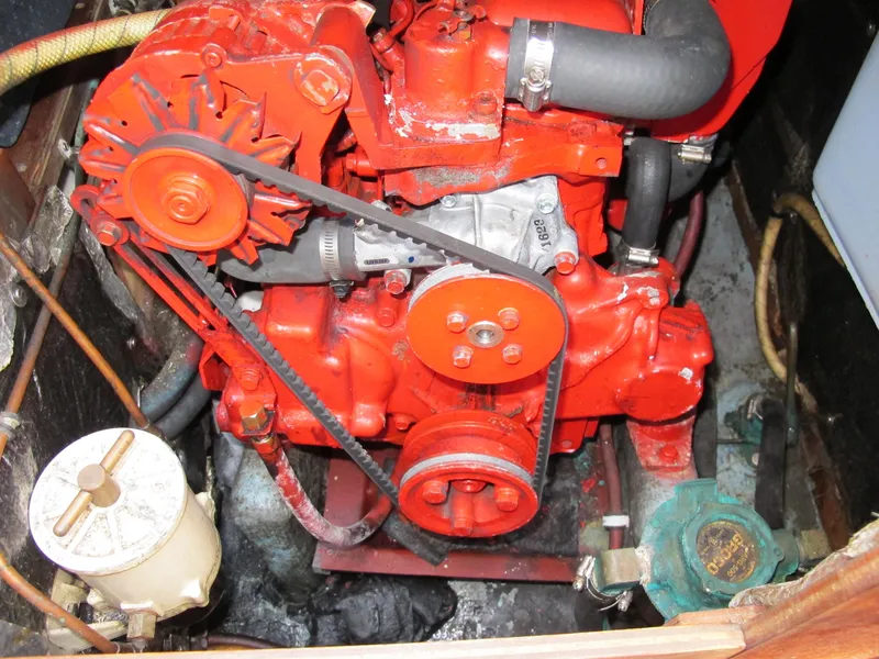 Slide: The Image of Red engine of a 1987 Sabre 34 sailboat, featuring belts and hoses. - 12