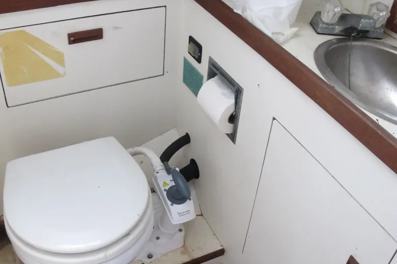 Slide: The Image of 1987 Sabre 34 boat bathroom with toilet, sink, and storage. - 17