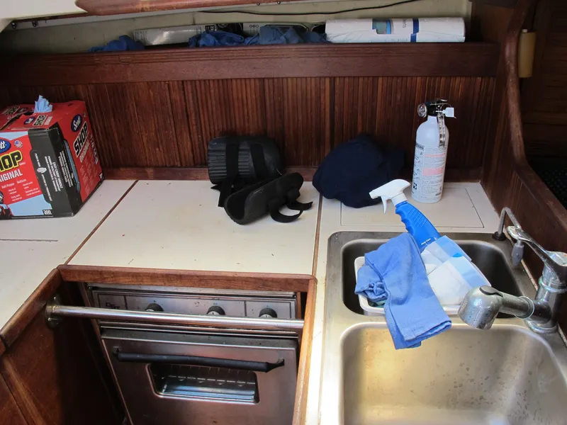 Slide: The Image of 1987 Sabre 34 yacht kitchen with stove, sink, and cleaning supplies. - 7
