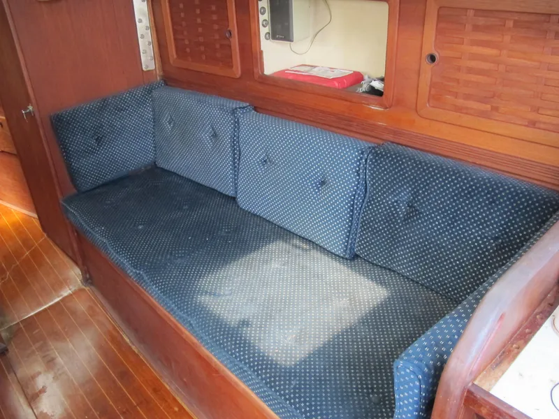 Slide: The Image of 1987 Sabre 34 sailboat interior with blue cushioned seating and wooden cabinetry. - 9