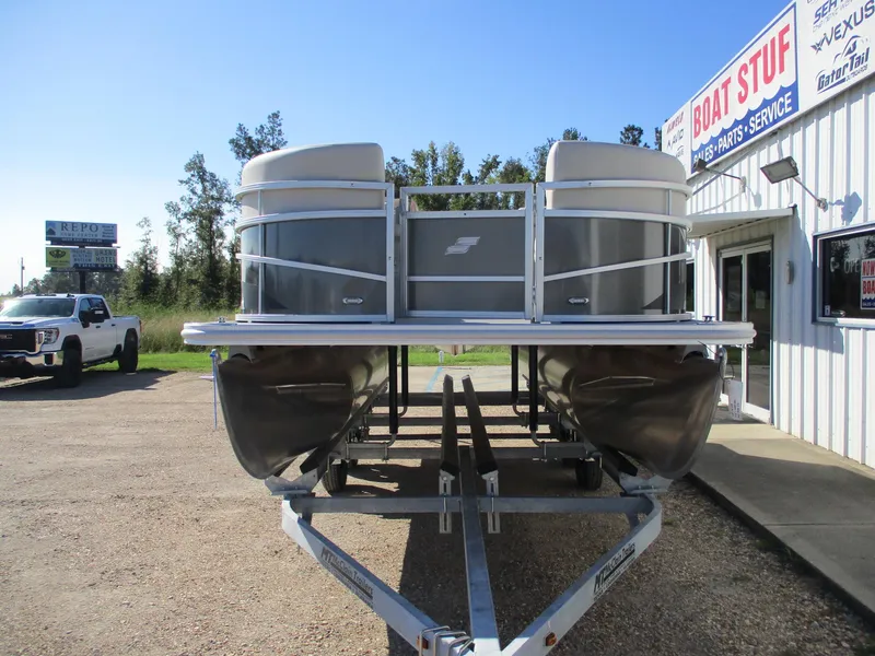 Slide: The Image of 2025 Starcraft LX 20 CB pontoon boat on trailer outside dealership. - 2