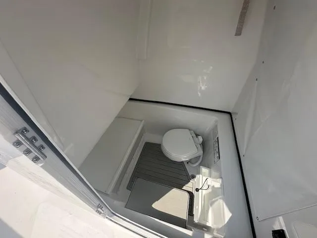 Slide: The Image of 2025 Sportsman 282 Open boat interior with compact marine toilet and storage area. - 15