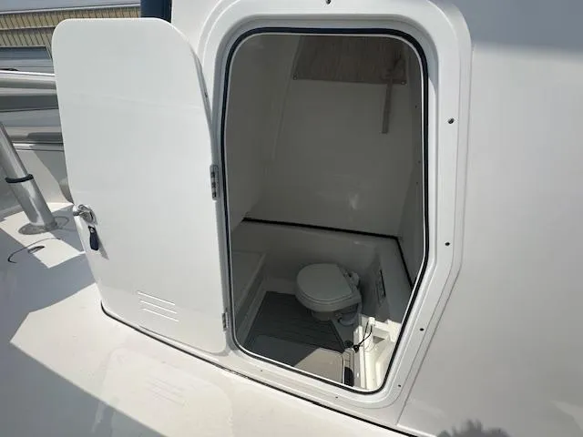 Slide: The Image of 2025 Sportsman 282 Open boat interior with open door revealing compact marine toilet. - 16