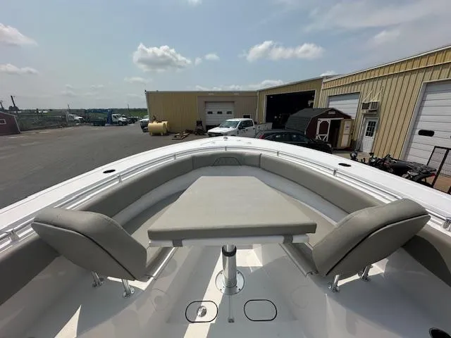 Slide: The Image of 2025 Sportsman 282 Open boat with seating and table, docked near industrial buildings. - 17