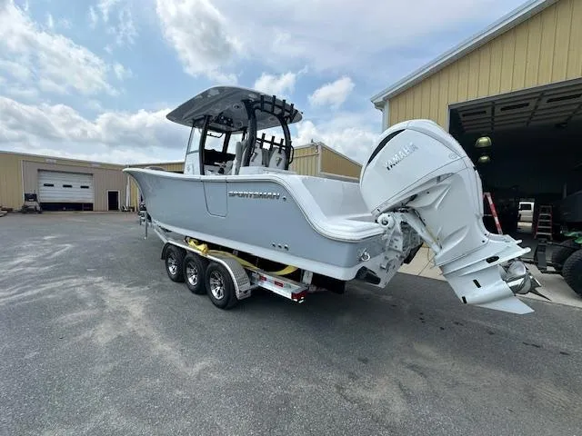Slide: The Image of 2025 Sportsman 282 Open boat on trailer, parked near warehouse under cloudy sky. - 3