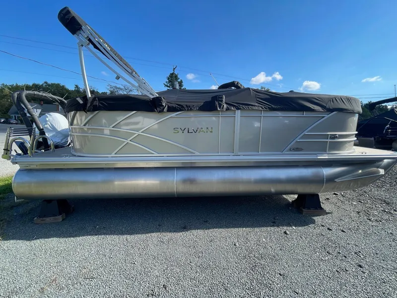 The Image of 2025 Sylvan 820 Mirage Cruise pontoon boat on gravel lot under clear blue sky. - 0