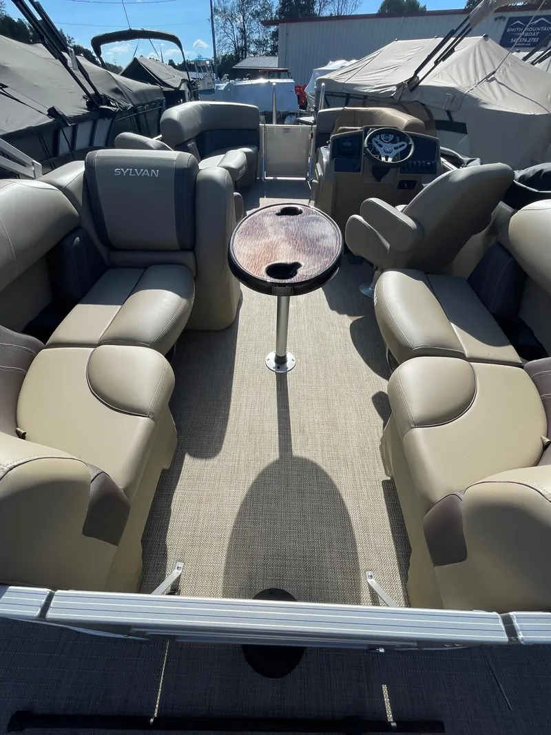 Slide: The Image of 2025 Sylvan 820 Mirage Cruise interior with beige seating and central table. - 14