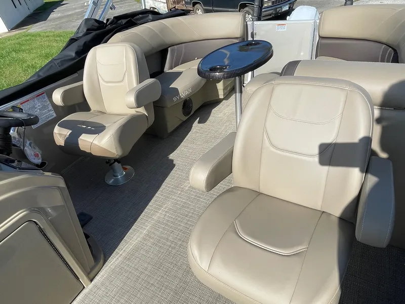 Slide: The Image of 2025 Sylvan 820 Mirage Cruise interior with beige seating and a small table. - 8