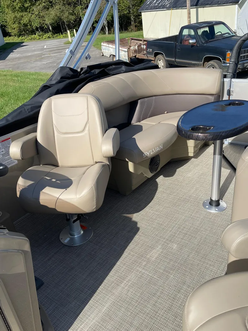 Slide: The Image of 2025 Sylvan 820 Mirage Cruise boat interior with beige seating and table. - 9