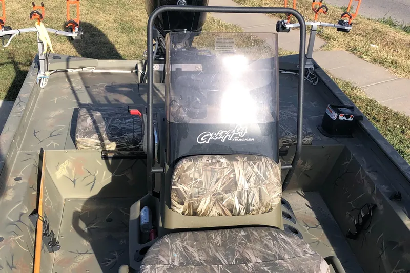 Slide: The Image of 2022 Tracker Grizzly 1860 CC boat with camouflage seats and console, parked outdoors. - 12