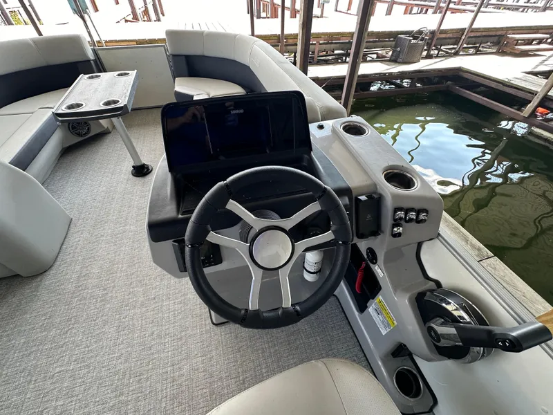 Slide: The Image of 2024 Harris FloteBote HCX 23 boat interior with steering wheel and seating area. - 11