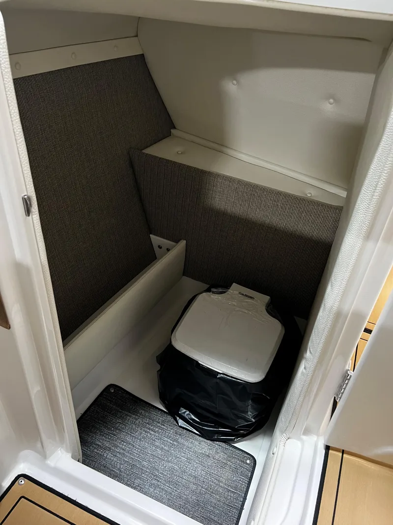 Slide: The Image of 2021 Cobalt 23SC boat interior with compact toilet and storage area. - 12