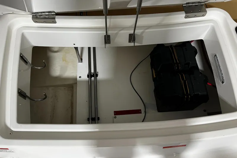 Slide: The Image of 2021 Cobalt 23SC boat storage compartment with battery and hooks. - 14