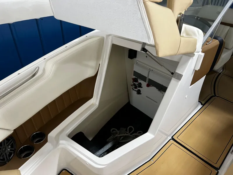 Slide: The Image of 2021 Cobalt 23SC boat interior storage compartment with beige seating and wood accents. - 9