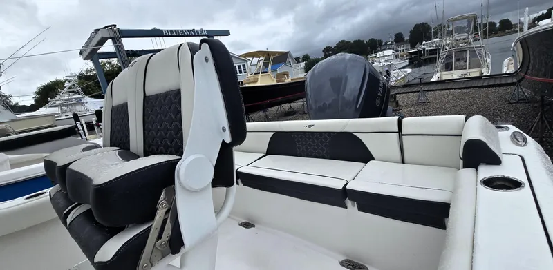 Slide: The Image of 2023 Tidewater 232 SS boat interior with cushioned seating at a marina. - 5