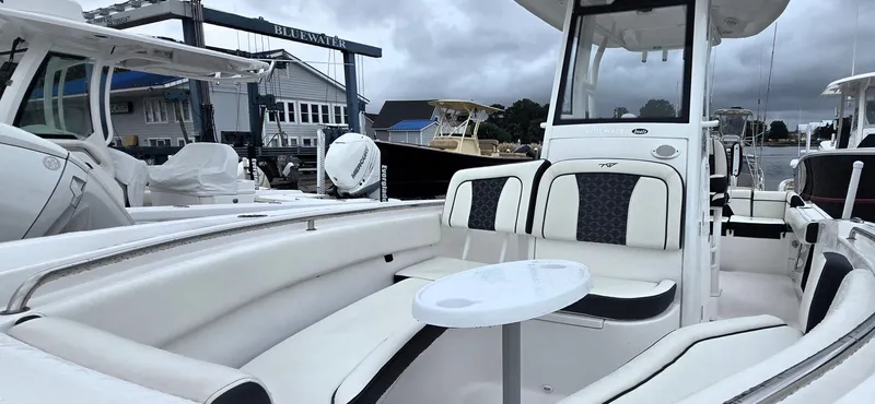 Slide: The Image of 2023 Tidewater 232 SS boat with white seating and table, docked at a marina. - 7